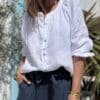 Chemise en lin blanche Albane – Coupe droite ample et boutons nacrés Élégante et confortable, la chemise Albane en lin est un choix parfait pour un look chic et décontracté. Description La chemise en lin blanche Albane est une pièce intemporelle qui se distingue par sa coupe droite ample et son col Mao. Confectionnée dans un lin léger et respirant, elle est idéale pour la saison chaude. Son tissu naturel offre une sensation de confort toute la journée. Les manches longues fermées par des boutons nacrés ajoutent une touche élégante à la chemise. Les boutons nacrés complètent parfaitement le style minimaliste de cette pièce. La taille unique convient aux tailles allant du 36 au 42, s'adaptant ainsi à une large gamme de morphologies. Fabriquée en Italie, cette chemise incarne l'art de la confection italienne avec une attention particulière aux détails et à la qualité des matériaux. Facile à porter, elle peut être associée à un jean pour un look décontracté ou à un pantalon fluide pour une allure plus élégante. Lin léger et respirant pour plus de confort Coupe droite ample pour une silhouette fluide Col Mao pour une touche moderne et chic Manches longues fermées par des boutons nacrés Taille unique (convient du 36 au 42) Fabrication italienne de haute qualité Couleur blanche intemporelle Un essentiel à adopter pour un look élégant et décontracté. Détails produit Coupe : Droite ample Matière : Lin naturel Manches : Longues avec boutons nacrés Col : Mao Boutons : Nacrés Couleur : Blanche Origine : Fabrication italienne Saison : Printemps / Été