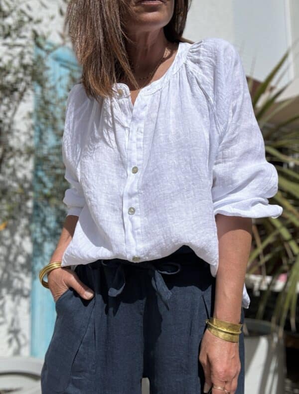 Chemise en lin blanche Albane – Coupe droite ample et boutons nacrés Élégante et confortable, la chemise Albane en lin est un choix parfait pour un look chic et décontracté. Description La chemise en lin blanche Albane est une pièce intemporelle qui se distingue par sa coupe droite ample et son col Mao. Confectionnée dans un lin léger et respirant, elle est idéale pour la saison chaude. Son tissu naturel offre une sensation de confort toute la journée. Les manches longues fermées par des boutons nacrés ajoutent une touche élégante à la chemise. Les boutons nacrés complètent parfaitement le style minimaliste de cette pièce. La taille unique convient aux tailles allant du 36 au 42, s'adaptant ainsi à une large gamme de morphologies. Fabriquée en Italie, cette chemise incarne l'art de la confection italienne avec une attention particulière aux détails et à la qualité des matériaux. Facile à porter, elle peut être associée à un jean pour un look décontracté ou à un pantalon fluide pour une allure plus élégante. Lin léger et respirant pour plus de confort Coupe droite ample pour une silhouette fluide Col Mao pour une touche moderne et chic Manches longues fermées par des boutons nacrés Taille unique (convient du 36 au 42) Fabrication italienne de haute qualité Couleur blanche intemporelle Un essentiel à adopter pour un look élégant et décontracté. Détails produit Coupe : Droite ample Matière : Lin naturel Manches : Longues avec boutons nacrés Col : Mao Boutons : Nacrés Couleur : Blanche Origine : Fabrication italienne Saison : Printemps / Été
