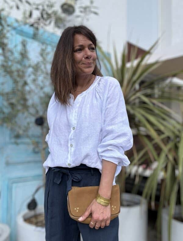 Chemise en lin blanche Albane – Coupe droite ample et boutons nacrés Élégante et confortable, la chemise Albane en lin est un choix parfait pour un look chic et décontracté. Description La chemise en lin blanche Albane est une pièce intemporelle qui se distingue par sa coupe droite ample et son col Mao. Confectionnée dans un lin léger et respirant, elle est idéale pour la saison chaude. Son tissu naturel offre une sensation de confort toute la journée. Les manches longues fermées par des boutons nacrés ajoutent une touche élégante à la chemise. Les boutons nacrés complètent parfaitement le style minimaliste de cette pièce. La taille unique convient aux tailles allant du 36 au 42, s'adaptant ainsi à une large gamme de morphologies. Fabriquée en Italie, cette chemise incarne l'art de la confection italienne avec une attention particulière aux détails et à la qualité des matériaux. Facile à porter, elle peut être associée à un jean pour un look décontracté ou à un pantalon fluide pour une allure plus élégante. Lin léger et respirant pour plus de confort Coupe droite ample pour une silhouette fluide Col Mao pour une touche moderne et chic Manches longues fermées par des boutons nacrés Taille unique (convient du 36 au 42) Fabrication italienne de haute qualité Couleur blanche intemporelle Un essentiel à adopter pour un look élégant et décontracté. Détails produit Coupe : Droite ample Matière : Lin naturel Manches : Longues avec boutons nacrés Col : Mao Boutons : Nacrés Couleur : Blanche Origine : Fabrication italienne Saison : Printemps / Été