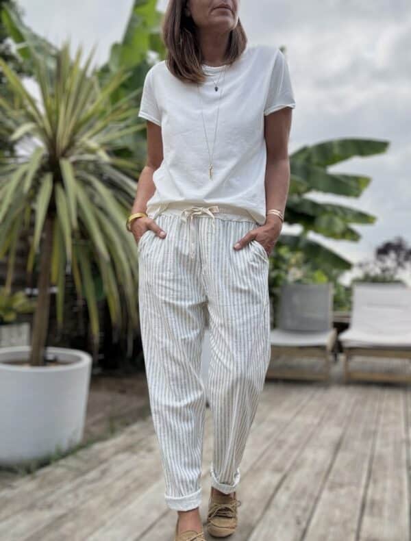 Pantalon Samba – Rayé kaki Réf. : SAMBA-KAKI En stock Pantalon rayé kaki, coupe droite. Taille élastique + lien. Coton et lin. Poches côtés et dos. Taille unique 36 à 40. Description Samba est un pantalon fluide rayé, fabriqué en Italie. Matière légère en coton et lin. Taille unique 36-40. Coupe droite et confortable. Idéal pour l’été. Détails du produit Nom : Samba Couleur : Rayé kaki Autre couleur : Existe en beige Taille : Élastique + lien à nouer Coupe : Droite, légèrement ample Matière : Coton et lin Taille unique : Convient du 36 au 40 Poches : Côtés + dos Fabrication : Italie Conseil style À porter avec un top en lin blanc, des sandales dorées et un panier en osier pour un look d'été parfait. #Samba #PantalonRayé #LookEstival #MadeInItaly #CotonLin