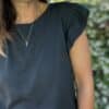 T-shirt Isaée – Noir Isaée revient dans son coloris noir intemporel. Un t-shirt basique, chic et féminin à avoir absolument. Couleur : noir (aussi disponible en vanille, camel, jean, marine, terracotta) Matière : coton doux Col : rond Manches : petit volant discret Coupe : droite Taille unique : convient du 36 au 40 Fabrication : italienne Une pièce qui allie élégance et confort. À porter au quotidien ou pour une allure plus habillée.