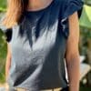 T-shirt Isaée – Noir Isaée revient dans son coloris noir intemporel. Un t-shirt basique, chic et féminin à avoir absolument. Couleur : noir (aussi disponible en vanille, camel, jean, marine, terracotta) Matière : coton doux Col : rond Manches : petit volant discret Coupe : droite Taille unique : convient du 36 au 40 Fabrication : italienne Une pièce qui allie élégance et confort. À porter au quotidien ou pour une allure plus habillée.
