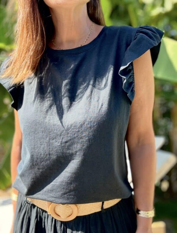 T-shirt Isaée – Noir Isaée revient dans son coloris noir intemporel. Un t-shirt basique, chic et féminin à avoir absolument. Couleur : noir (aussi disponible en vanille, camel, jean, marine, terracotta) Matière : coton doux Col : rond Manches : petit volant discret Coupe : droite Taille unique : convient du 36 au 40 Fabrication : italienne Une pièce qui allie élégance et confort. À porter au quotidien ou pour une allure plus habillée.
