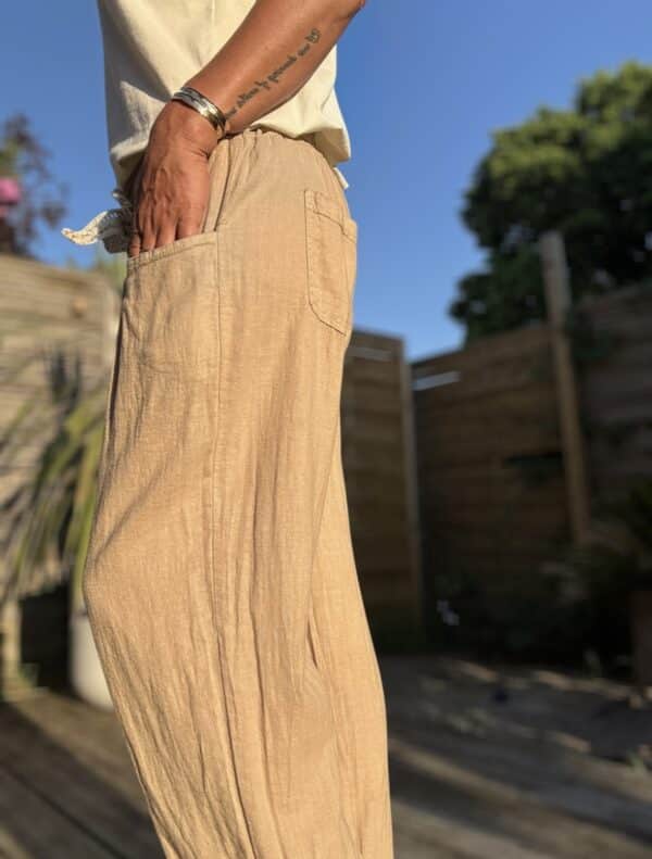 Azélie – Pantalon Camel Léger en Lin et Coton Découvrez Azeli, le pantalon camel pensé pour l’été. Confectionné en 50% coton et 50% lin, il séduit par sa légèreté et son tombé fluide. Sa coupe droite ample convient à toutes les silhouettes. La taille élastique assure confort et maintien sans serrer. En bonus, une ceinture amovible en jute et coton pour un look naturel et raffiné. Ce pantalon dispose de poches pratiques à l’avant et à l’arrière. Sa taille unique convient du 36 au 42. Il est fabriqué en Italie, avec soin et exigence. À associer avec un top léger, un débardeur ou une chemise rentrée. Idéal en ville comme en vacances. Coloris : camel Matière : 50% coton – 50% lin Ceinture amovible (jute & coton) Taille élastique Coupe droite et ample Taille unique : convient du 36 au 40 Fabriqué en Italie