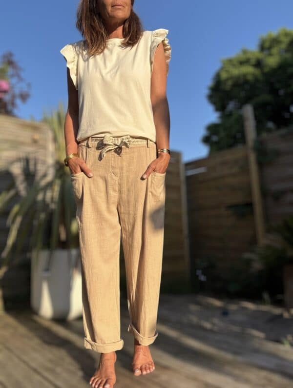 Azélie – Pantalon Camel Léger en Lin et Coton Découvrez Azeli, le pantalon camel pensé pour l’été. Confectionné en 50% coton et 50% lin, il séduit par sa légèreté et son tombé fluide. Sa coupe droite ample convient à toutes les silhouettes. La taille élastique assure confort et maintien sans serrer. En bonus, une ceinture amovible en jute et coton pour un look naturel et raffiné. Ce pantalon dispose de poches pratiques à l’avant et à l’arrière. Sa taille unique convient du 36 au 40. Il est fabriqué en Italie, avec soin et exigence. À associer avec un top léger, un débardeur ou une chemise rentrée. Idéal en ville comme en vacances. Coloris : camel Matière : 50% coton – 50% lin Ceinture amovible (jute & coton) Taille élastique Coupe droite et ample Taille unique : convient du 36 au 42 Fabriqué en Italie
