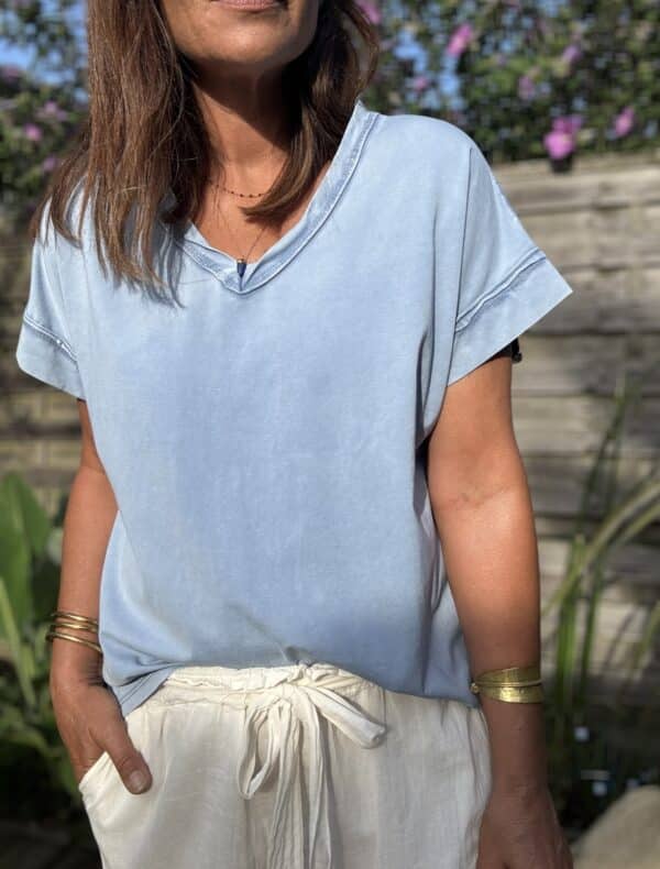 T-shirt LIOR – Jean Clair Le t-shirt LIOR en coloris jean clair est confectionné en Italie dans un coton doux légèrement délavé pour un effet vintage élégant. Sa coupe ample assure un confort optimal et convient à une taille unique allant du 36 au 44. Son col V met en valeur le décolleté tandis que les détails couture sur les manches et le col apportent de la finesse à l’ensemble. Les manches courtes, légèrement tombantes, offrent une silhouette fluide et féminine. Ce coloris jean clair s’accorde parfaitement avec du blanc, du beige, du camel ou des motifs floraux. Pour un style détente ou une tenue citadine, LIOR s’adapte à toutes vos envies. Disponible également en kaki, framboise et camel. Composition : 100% coton Coupe : ample Coloris : jean clair Taille unique : convient du 36 au 44 Fabriqué en Italie
