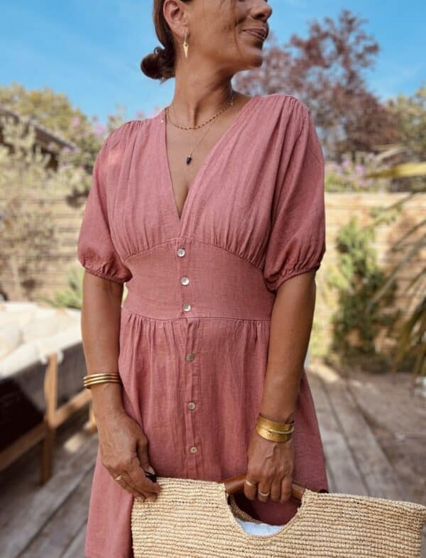 Robe SOLINE – Élégance fluide et féminine Craquez pour la robe Soline, une pièce fluide et légère en viscose et lin, parfaite pour la belle saison. Mix de viscose et lin naturel Coupe mi-longue flatteuse Décolleté plongeant féminin Fermeture intégrale par boutons nacrés Manches courtes avec finition élastiquée Élastique discret au dos pour plus de confort Découpe devant légèrement évasée pour camoufler le ventre Matière respirante et agréable à porter Taille unique (convient du 36 au 40) Fabrication italienne À associer avec des sandales, des bijoux dorés et un panier pour un look bohème-chic sans effort.