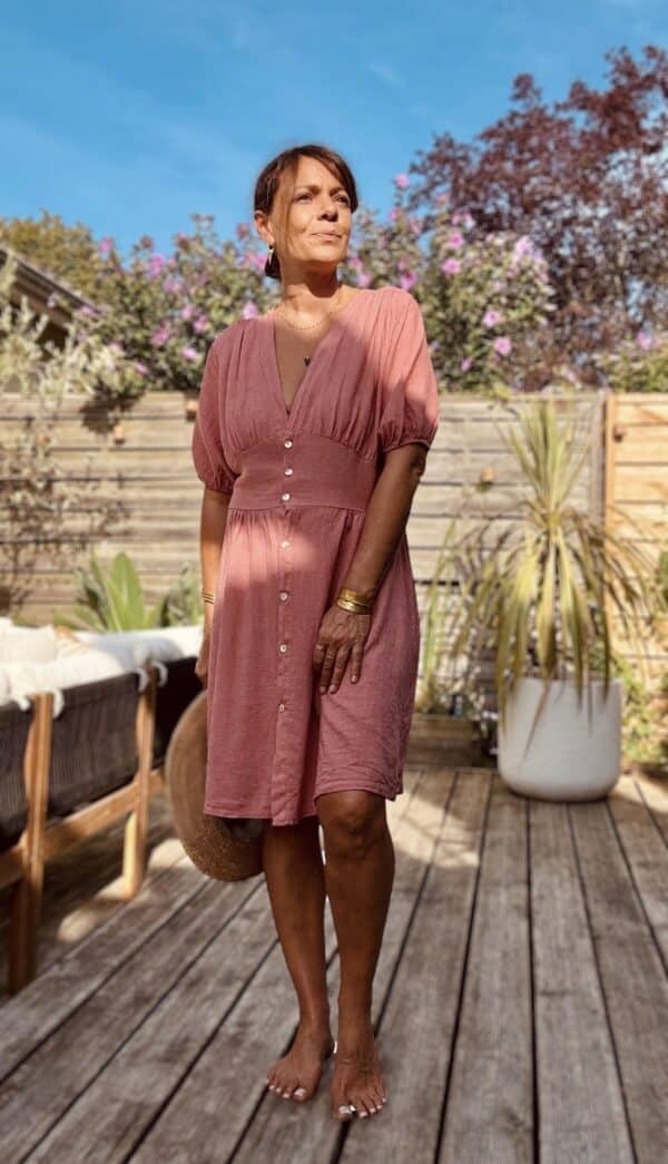 Robe SOLINE – Élégance fluide et féminine Craquez pour la robe Soline, une pièce fluide et légère en viscose et lin, parfaite pour la belle saison. Mix de viscose et lin naturel Coupe mi-longue flatteuse Décolleté plongeant féminin Fermeture intégrale par boutons nacrés Manches courtes avec finition élastiquée Élastique discret au dos pour plus de confort Découpe devant légèrement évasée pour camoufler le ventre Matière respirante et agréable à porter Taille unique (convient du 36 au 40) Fabrication italienne À associer avec des sandales, des bijoux dorés et un panier pour un look bohème-chic sans effort.