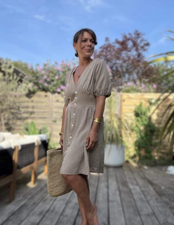 Robe mi-longue Soline – Coloris camel Voici la robe Soline en camel, une teinte chaude et naturelle qui sublime la silhouette avec élégance. Composition fluide : viscose & lin Décolleté plongeant délicat Fermeture sur le devant avec boutons nacrés Manches courtes finies par un élastique léger Coupe mi-longue flatteuse et fluide Élastique souple au dos pour plus d’aisance Découpe légèrement plus ample sur le ventre Coloris camel facile à porter et associer Taille unique (du 36 au 40) Confection italienne Parfait avec des sandales dorées, un panier et un chapeau de paille pour un look 100 % bohème-chic.