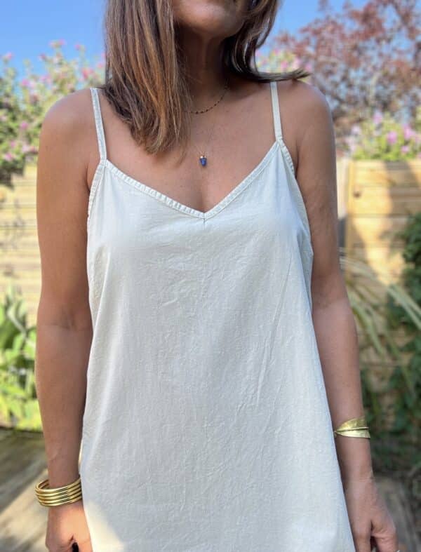 Fond de robe BERTIY – Voile de coton – Beige clair Le fond de robe BERTIY est une pièce indispensable pour accompagner vos robes d'été en toute discrétion. Confectionné en voile de coton ultra léger, il évite les transparences tout en préservant la fluidité de votre tenue. Son coloris beige clair reste neutre et s'accorde facilement avec vos pièces estivales. Il reste totalement invisible sous les tissus clairs. Ses bretelles réglables vous permettent d'ajuster la hauteur avec précision pour un confort optimal. Sa coupe droite épouse la silhouette sans la mouler. Il reste confortable toute la journée, même par forte chaleur. Nous le conseillons tout particulièrement sous l’ensemble MAE en lin et coton. Il préserve la légèreté du look tout en évitant toute transparence. Fabriqué en Italie, il offre une belle qualité de finition et un tombé élégant. C’est une pièce durable et facile à associer. En résumé : un fond de robe léger, féminin, confortable, à adopter pour vos tenues bohèmes-chic. Chez Les Marques de Lilo, on aime les pièces simples, efficaces et toujours pleines de féminité. BERTIY en est l'exemple parfait.