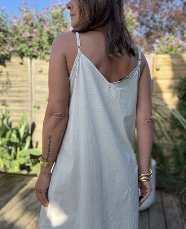 Fond de robe BERTIY – Voile de coton – Beige clair Le fond de robe BERTIY est une pièce indispensable pour accompagner vos robes d'été en toute discrétion. Confectionné en voile de coton ultra léger, il évite les transparences tout en préservant la fluidité de votre tenue. Son coloris beige clair reste neutre et s'accorde facilement avec vos pièces estivales. Il reste totalement invisible sous les tissus clairs. Ses bretelles réglables vous permettent d'ajuster la hauteur avec précision pour un confort optimal. Sa coupe droite épouse la silhouette sans la mouler. Il reste confortable toute la journée, même par forte chaleur. Nous le conseillons tout particulièrement sous l’ensemble MAE en lin et coton. Il préserve la légèreté du look tout en évitant toute transparence. Fabriqué en Italie, il offre une belle qualité de finition et un tombé élégant. C’est une pièce durable et facile à associer. En résumé : un fond de robe léger, féminin, confortable, à adopter pour vos tenues bohèmes-chic. Chez Les Marques de Lilo, on aime les pièces simples, efficaces et toujours pleines de féminité. BERTIY en est l'exemple parfait.