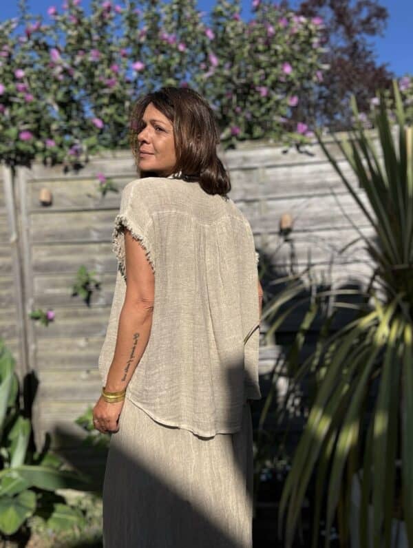 Chemise MAE – Lin et coton – Taupe La chemise MAE est une pièce phare de notre collection estivale. Son style bohème-chic s’allie parfaitement à la simplicité et la féminité que nous aimons tant. Confectionnée en 50 % lin et 50 % coton, elle offre une matière légère, respirante et très agréable à porter. Sa coupe ample convient à toutes les morphologies, sans jamais alourdir la silhouette. Sans manches, elle dévoile joliment les épaules. Le col Mao lui apporte une touche d’élégance naturelle. Elle se ferme par une série de boutons nacrés, discrets et raffinés. Sa finition frangée souligne l’ensemble d’une note bohème, moderne et douce. Le coloris taupe, à la fois neutre et chaleureux, se marie facilement avec vos tenues estivales. Cette chemise est proposée en taille unique, et convient du 36 au 42. Grâce à sa coupe fluide, elle s’adapte à chaque silhouette avec naturel. Pour un ensemble coordonné, portez-la avec la jupe MAE assortie. Ensemble, elles créent un total look bohème irrésistible, parfait pour la saison. Fabriquée en Italie avec soin et amour, cette chemise incarne l’esprit des Marques de Lilo : simplicité, efficacité, féminité.