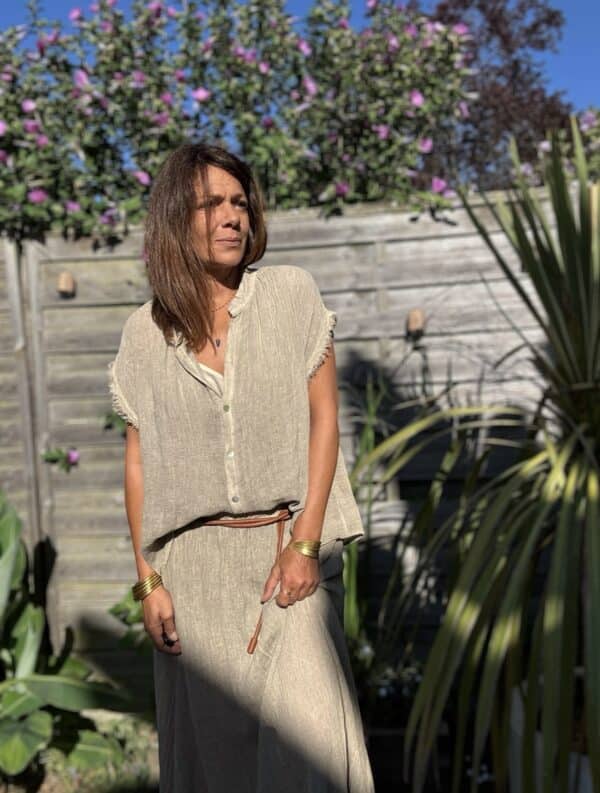 Chemise MAE – Lin et coton – Taupe La chemise MAE est une pièce phare de notre collection estivale. Son style bohème-chic s’allie parfaitement à la simplicité et la féminité que nous aimons tant. Confectionnée en 50 % lin et 50 % coton, elle offre une matière légère, respirante et très agréable à porter. Sa coupe ample convient à toutes les morphologies, sans jamais alourdir la silhouette. Sans manches, elle dévoile joliment les épaules. Le col Mao lui apporte une touche d’élégance naturelle. Elle se ferme par une série de boutons nacrés, discrets et raffinés. Sa finition frangée souligne l’ensemble d’une note bohème, moderne et douce. Le coloris taupe, à la fois neutre et chaleureux, se marie facilement avec vos tenues estivales. Cette chemise est proposée en taille unique, et convient du 36 au 42. Grâce à sa coupe fluide, elle s’adapte à chaque silhouette avec naturel. Pour un ensemble coordonné, portez-la avec la jupe MAE assortie. Ensemble, elles créent un total look bohème irrésistible, parfait pour la saison. Fabriquée en Italie avec soin et amour, cette chemise incarne l’esprit des Marques de Lilo : simplicité, efficacité, féminité.