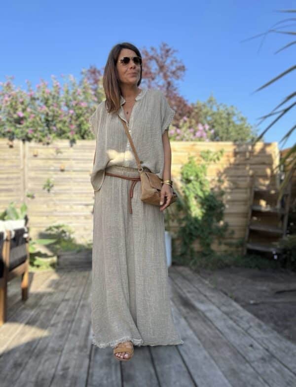 Chemise MAE – Lin et coton – Taupe La chemise MAE est une pièce phare de notre collection estivale. Son style bohème-chic s’allie parfaitement à la simplicité et la féminité que nous aimons tant. Confectionnée en 50 % lin et 50 % coton, elle offre une matière légère, respirante et très agréable à porter. Sa coupe ample convient à toutes les morphologies, sans jamais alourdir la silhouette. Sans manches, elle dévoile joliment les épaules. Le col Mao lui apporte une touche d’élégance naturelle. Elle se ferme par une série de boutons nacrés, discrets et raffinés. Sa finition frangée souligne l’ensemble d’une note bohème, moderne et douce. Le coloris taupe, à la fois neutre et chaleureux, se marie facilement avec vos tenues estivales. Cette chemise est proposée en taille unique, et convient du 36 au 42. Grâce à sa coupe fluide, elle s’adapte à chaque silhouette avec naturel. Pour un ensemble coordonné, portez-la avec la jupe MAE assortie. Ensemble, elles créent un total look bohème irrésistible, parfait pour la saison. Fabriquée en Italie avec soin et amour, cette chemise incarne l’esprit des Marques de Lilo : simplicité, efficacité, féminité.