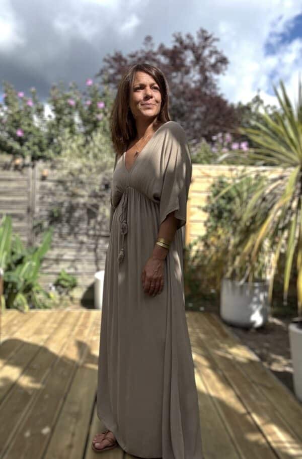 Robe LENAE camel – Longue, fluide et élégante Adoptez la robe LENAE camel, conçue en viscose fluide pour un confort optimal. Sa coupe droite et évasée flatte toutes les silhouettes, tandis que son décolleté en V sublime le port. L'élastique sous la poitrine et le lien à nouer avec pompons permettent un ajustement parfait. Cette robe longue se porte facilement en journée ou en soirée, parfaite pour les beaux jours. Fabriquée en Italie, elle offre une qualité et une finition irréprochables. Disponible en taille unique, elle convient du 36 au 40. Le coloris camel apporte une touche chaude et intemporelle à votre garde-robe. Attention, les stocks sont limités.