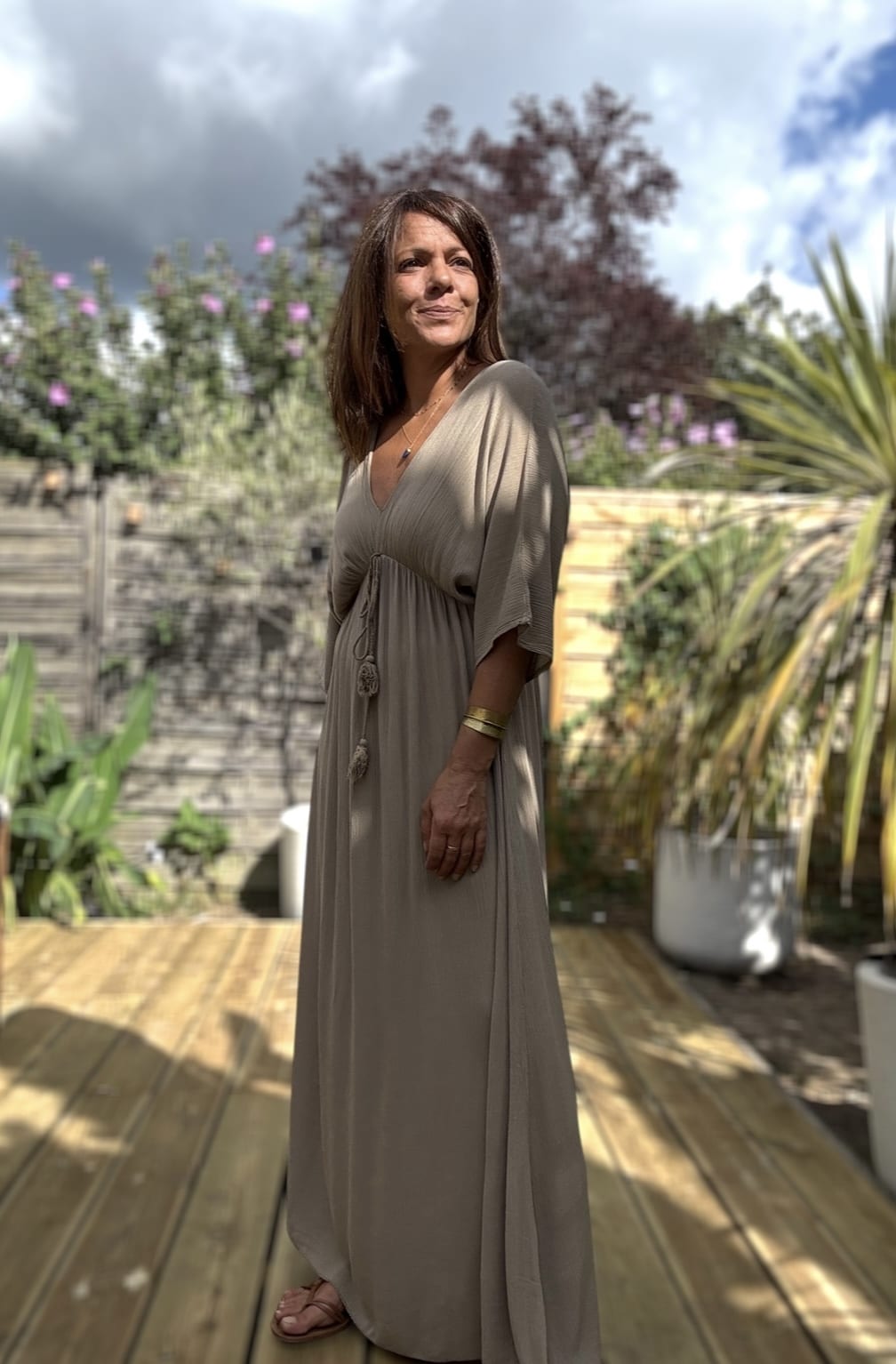 Robe LENAE camel – Longue, fluide et élégante Adoptez la robe LENAE camel, conçue en viscose fluide pour un confort optimal. Sa coupe droite et évasée flatte toutes les silhouettes, tandis que son décolleté en V sublime le port. L'élastique sous la poitrine et le lien à nouer avec pompons permettent un ajustement parfait. Cette robe longue se porte facilement en journée ou en soirée, parfaite pour les beaux jours. Fabriquée en Italie, elle offre une qualité et une finition irréprochables. Disponible en taille unique, elle convient du 36 au 40. Le coloris camel apporte une touche chaude et intemporelle à votre garde-robe. Attention, les stocks sont limités.