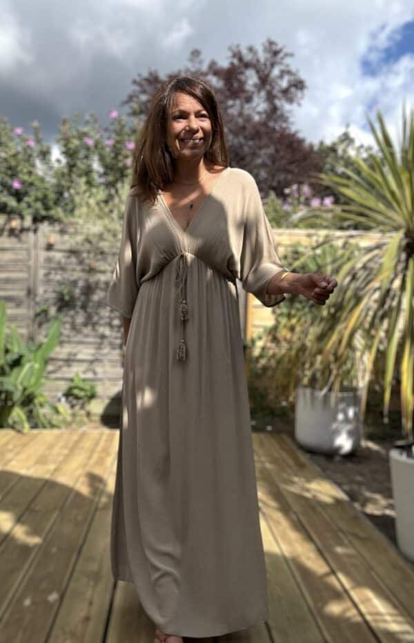 Robe LENAE camel – Longue, fluide et élégante Adoptez la robe LENAE camel, conçue en viscose fluide pour un confort optimal. Sa coupe droite et évasée flatte toutes les silhouettes, tandis que son décolleté en V sublime le port. L'élastique sous la poitrine et le lien à nouer avec pompons permettent un ajustement parfait. Cette robe longue se porte facilement en journée ou en soirée, parfaite pour les beaux jours. Fabriquée en Italie, elle offre une qualité et une finition irréprochables. Disponible en taille unique, elle convient du 36 au 40. Le coloris camel apporte une touche chaude et intemporelle à votre garde-robe. Attention, les stocks sont limités.