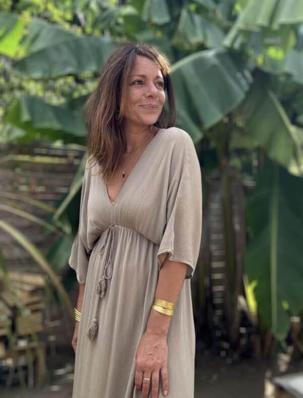 Robe LENAE camel – Longue, fluide et élégante Adoptez la robe LENAE camel, conçue en viscose fluide pour un confort optimal. Sa coupe droite et évasée flatte toutes les silhouettes, tandis que son décolleté en V sublime le port. L'élastique sous la poitrine et le lien à nouer avec pompons permettent un ajustement parfait. Cette robe longue se porte facilement en journée ou en soirée, parfaite pour les beaux jours. Fabriquée en Italie, elle offre une qualité et une finition irréprochables. Disponible en taille unique, elle convient du 36 au 40. Le coloris camel apporte une touche chaude et intemporelle à votre garde-robe. Attention, les stocks sont limités.