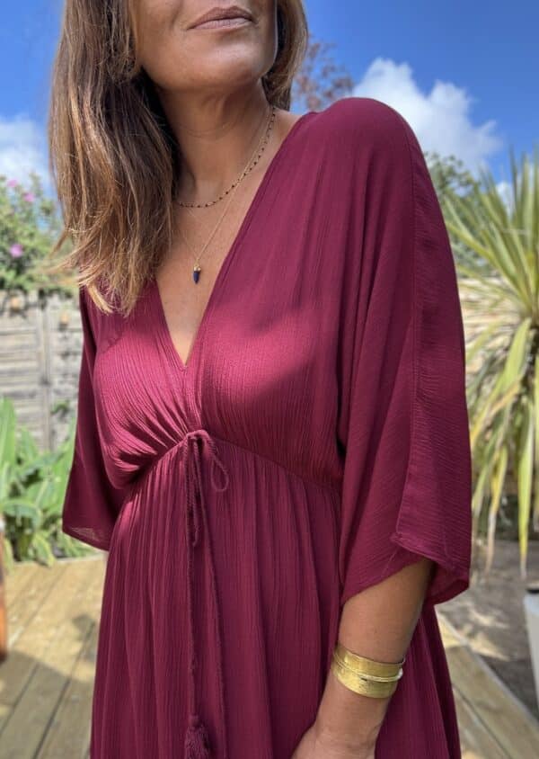 Robe longue fluide bordeaux – LENAE Découvrez la robe LENAE bordeaux, longue et fluide, au tombé naturel et à la couleur profonde. Elle met en valeur chaque silhouette avec douceur et élégance. Sa matière en viscose assure confort, légèreté et fluidité. Elle est idéale pour l'été ou la mi-saison. Le décolleté en V devant et au dos structure la robe avec féminité. L'élasticité fine sous la poitrine souligne subtilement la taille. Un lien à nouer, terminé par de jolis pompons, permet d’ajuster la coupe selon vos envies. Couleur : bordeaux Matière : viscose légère Décolleté : devant et dos Manches : courtes Ceinture : lien à pompons Coupe : droite, légèrement évasée Taille : unique (36 à 40) Fabrication : Italie Associez-la à des accessoires dorés, à une veste en jean ou un gilet léger pour les soirées d'été. LENAE prune, c’est la robe parfaite pour les beaux jours, les soirées, et les instants qui comptent. Edition limitée – dernière chance !