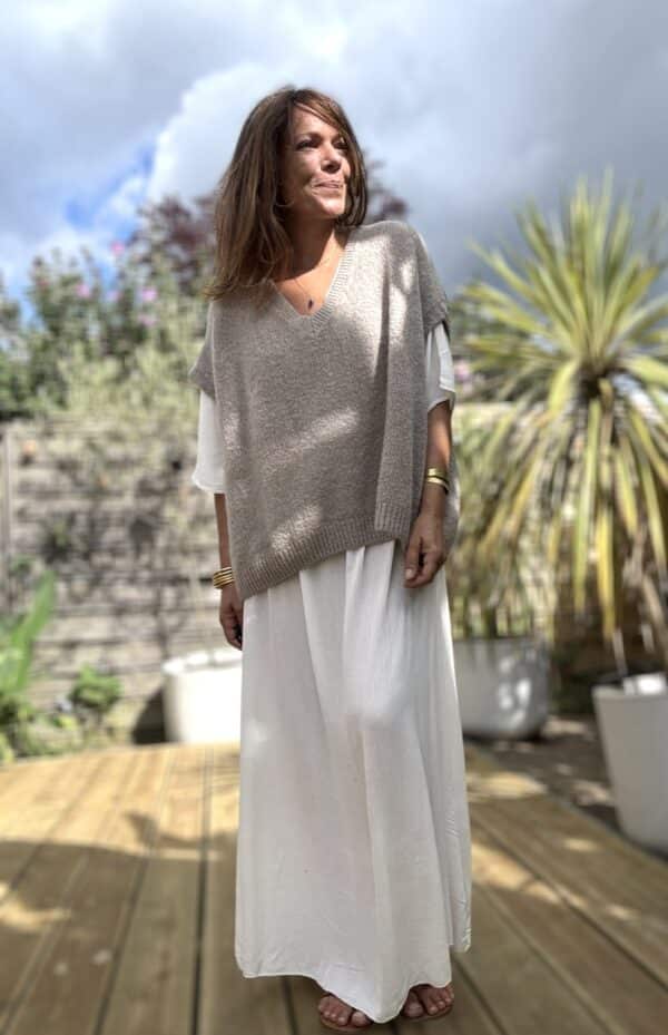 Robe longue fluide écrue – LENAE La robe LENAE écrue séduit par sa coupe longue, fluide et féminine. Elle offre un tomber naturel, parfait en toute occasion. Confectionnée en viscose légère, elle est agréable à porter même en plein été. Sa matière douce épouse les mouvements sans coller à la peau. Le décolleté en V se retrouve à l’avant comme à l’arrière, pour une touche féminine subtile. Sous la poitrine, un élastique fin souligne la taille sans comprimer. Un lien à nouer, orné de pompons, permet d’ajuster la robe avec charme et confort. Matière : viscose fluide Couleur : écrue Décolleté : devant et dos Manches : courtes Ceinture : lien à pompons Coupe : droite et évasée Taille : unique (36 à 40) Fabrication : Italie Associez-la à des sandales ou des espadrilles pour un look estival chic. Portez-la aussi en soirée avec une veste légère. ✨ Une robe pour briller au soleil, bouger librement, et se sentir belle en un clin d’œil. Attention : quantité très limitée !