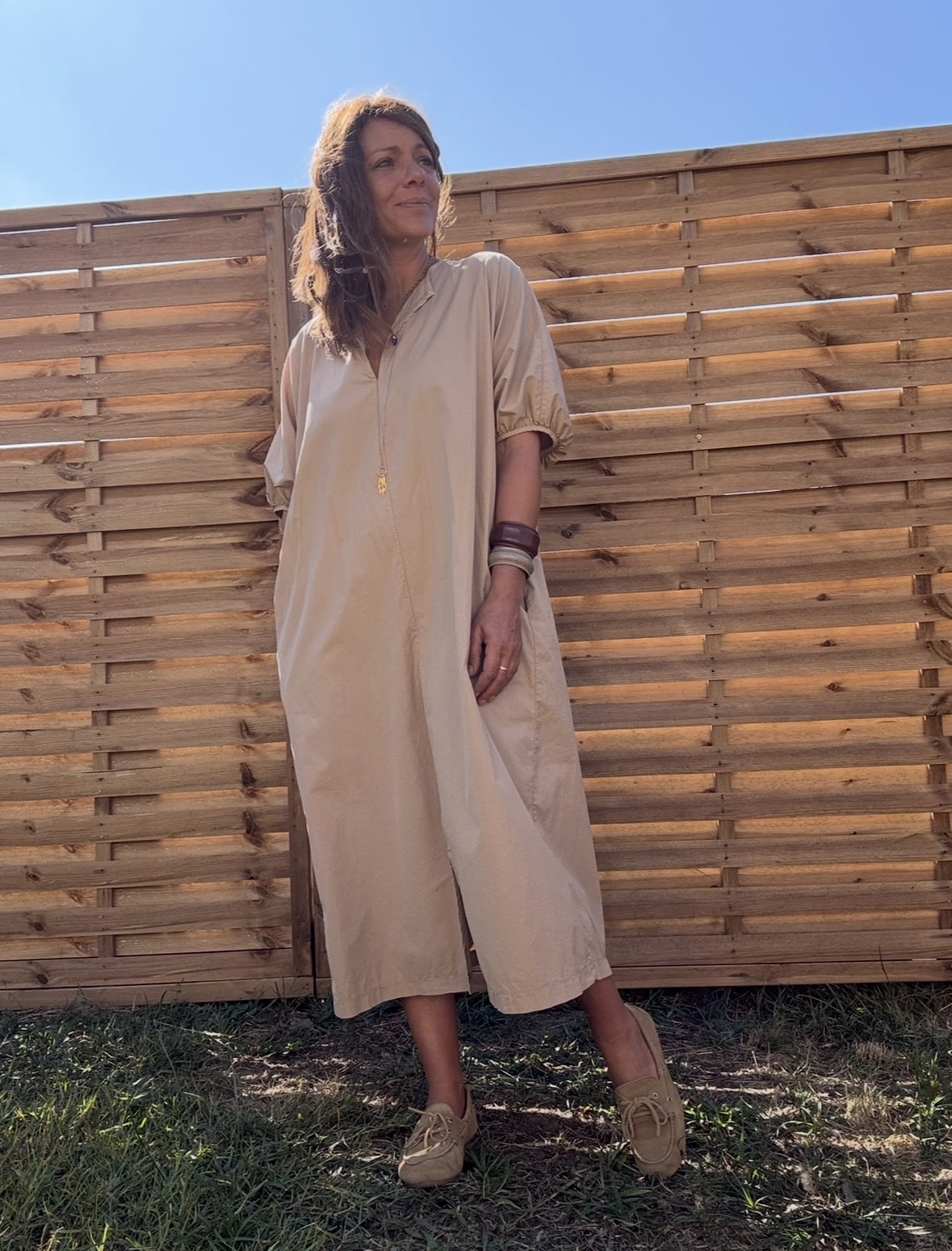 Robe longue Alba – coton beige – Taille unique Craquez pour la robe Alba, une robe longue et fluide en 100 % coton, au coloris beige doux et naturel. Sa coupe ample convient à toutes les morphologies (taille unique du 36 au 44). Son col V féminin, ses manches courtes et sa ceinture intégrée à nouer mettent subtilement en valeur la silhouette. Elle possède également des poches pratiques sur les côtés et une fente discrète à l’avant. Conçue en Italie, cette robe incarne le confort et l’élégance bohème. À porter aussi bien en ville qu’en vacances. Matière : 100 % coton Coloris : Beige Coupe : Longue, ample, col V Détails : Ceinture intégrée, fente devant, poches, manches courtes Taille unique : convient du 36 au 44 Fabrication : Italie Conseil style : associez-la à des sandales plates ou des espadrilles pour un look estival parfait. Quantités très limitées ! Ne manquez pas ce modèle incontournable de la saison.