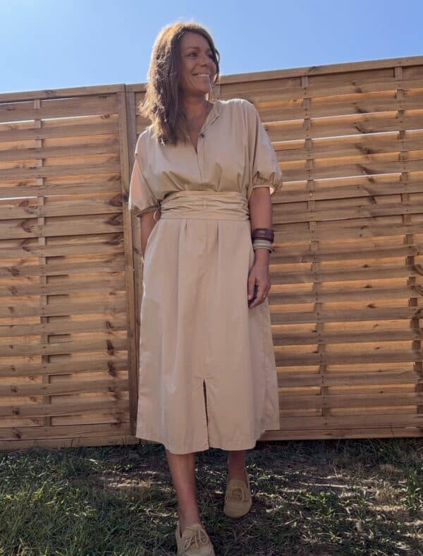 Robe longue Alba – coton beige – Taille unique Craquez pour la robe Alba, une robe longue et fluide en 100 % coton, au coloris beige doux et naturel. Sa coupe ample convient à toutes les morphologies (taille unique du 36 au 44). Son col V féminin, ses manches courtes et sa ceinture intégrée à nouer mettent subtilement en valeur la silhouette. Elle possède également des poches pratiques sur les côtés et une fente discrète à l’avant. Conçue en Italie, cette robe incarne le confort et l’élégance bohème. À porter aussi bien en ville qu’en vacances. Matière : 100 % coton Coloris : Beige Coupe : Longue, ample, col V Détails : Ceinture intégrée, fente devant, poches, manches courtes Taille unique : convient du 36 au 44 Fabrication : Italie Conseil style : associez-la à des sandales plates ou des espadrilles pour un look estival parfait. Quantités très limitées ! Ne manquez pas ce modèle incontournable de la saison.
