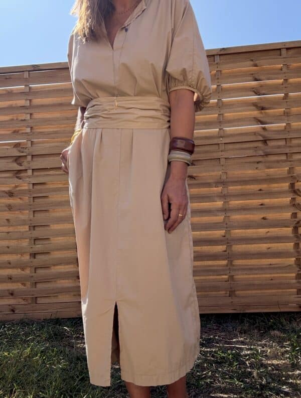 Robe longue Alba – coton beige – Taille unique Craquez pour la robe Alba, une robe longue et fluide en 100 % coton, au coloris beige doux et naturel. Sa coupe ample convient à toutes les morphologies (taille unique du 36 au 44). Son col V féminin, ses manches courtes et sa ceinture intégrée à nouer mettent subtilement en valeur la silhouette. Elle possède également des poches pratiques sur les côtés et une fente discrète à l’avant. Conçue en Italie, cette robe incarne le confort et l’élégance bohème. À porter aussi bien en ville qu’en vacances. Matière : 100 % coton Coloris : Beige Coupe : Longue, ample, col V Détails : Ceinture intégrée, fente devant, poches, manches courtes Taille unique : convient du 36 au 44 Fabrication : Italie Conseil style : associez-la à des sandales plates ou des espadrilles pour un look estival parfait. Quantités très limitées ! Ne manquez pas ce modèle incontournable de la saison.