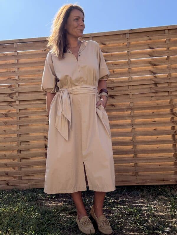 Robe longue Alba – coton beige – Taille unique Craquez pour la robe Alba, une robe longue et fluide en 100 % coton, au coloris beige doux et naturel. Sa coupe ample convient à toutes les morphologies (taille unique du 36 au 44). Son col V féminin, ses manches courtes et sa ceinture intégrée à nouer mettent subtilement en valeur la silhouette. Elle possède également des poches pratiques sur les côtés et une fente discrète à l’avant. Conçue en Italie, cette robe incarne le confort et l’élégance bohème. À porter aussi bien en ville qu’en vacances. Matière : 100 % coton Coloris : Beige Coupe : Longue, ample, col V Détails : Ceinture intégrée, fente devant, poches, manches courtes Taille unique : convient du 36 au 44 Fabrication : Italie Conseil style : associez-la à des sandales plates ou des espadrilles pour un look estival parfait. Quantités très limitées ! Ne manquez pas ce modèle incontournable de la saison.