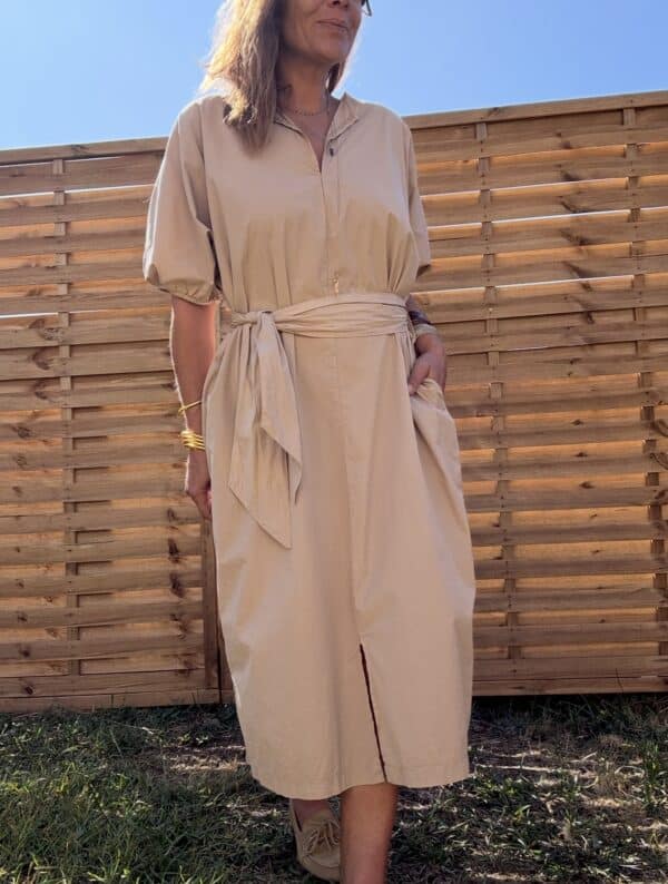 Robe longue Alba – coton beige – Taille unique Craquez pour la robe Alba, une robe longue et fluide en 100 % coton, au coloris beige doux et naturel. Sa coupe ample convient à toutes les morphologies (taille unique du 36 au 44). Son col V féminin, ses manches courtes et sa ceinture intégrée à nouer mettent subtilement en valeur la silhouette. Elle possède également des poches pratiques sur les côtés et une fente discrète à l’avant. Conçue en Italie, cette robe incarne le confort et l’élégance bohème. À porter aussi bien en ville qu’en vacances. Matière : 100 % coton Coloris : Beige Coupe : Longue, ample, col V Détails : Ceinture intégrée, fente devant, poches, manches courtes Taille unique : convient du 36 au 44 Fabrication : Italie Conseil style : associez-la à des sandales plates ou des espadrilles pour un look estival parfait. Quantités très limitées ! Ne manquez pas ce modèle incontournable de la saison.