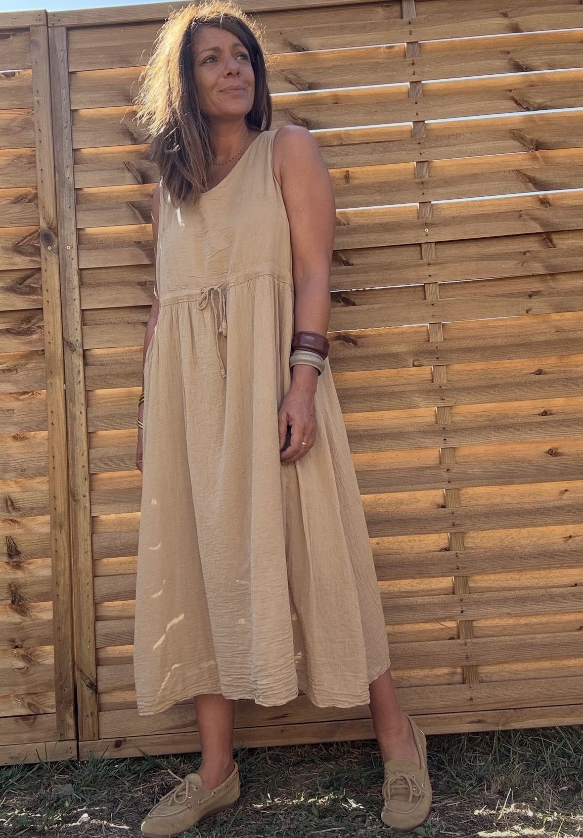 Robe ELYNE – voile de coton doublé, coloris camel Description La robe ELYNE allie légèreté, confort et élégance. En voile de coton doublé, elle est idéale pour la fin de l’été et l’automne. Sa coupe ample sans manche permet une grande liberté de mouvement. Grâce à son lien à nouer à la taille, elle se porte ample ou ceinturée. Ses poches ajoutent une touche de praticité. Le coloris camel réchauffe la silhouette, mais elle existe aussi en kaki et en marine. Détails du produit Matière : voile de coton doublé Sans manche Coupe ample Lien ajustable à la taille Poches discrètes sur les côtés Coloris : camel, kaki ou marine Taille unique (convient du 36 au 40) Fabrication italienne Conseils de style Portez la robe ELYNE seule en fin d’été, ou superposée avec un pull oversize à l’automne. Associez-la à des bottines, des baskets ou des sandales selon la saison. Entretien Lavage à froid ou cycle délicat Séchage à plat recommandé Repassage doux si nécessaire