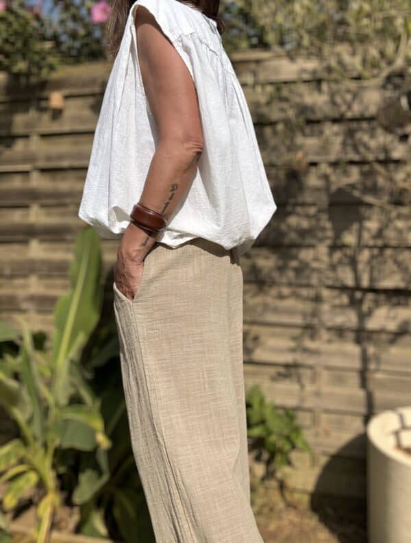 Pantalon Honoré – coton camel – coupe large Craquez pour le pantalon Honoré, un modèle large et fluide, confectionné dans un coton camel léger et agréable à porter. Sa coupe ample assure un style décontracté mais toujours élégant. Il convient parfaitement aux journées actives ou aux moments de détente. La taille élastique s’adapte naturellement à votre silhouette. Elle offre un confort optimal, du matin jusqu’au soir. Ce modèle en taille unique convient aux morphologies allant du 36 au 42. Il s’enfile facilement et épouse les formes sans les contraindre. Les poches latérales ajoutent une touche pratique à ce basique du dressing estival. Vous pouvez y glisser vos essentiels en toute simplicité. Grâce à sa matière légère en coton, ce pantalon reste respirant et agréable à porter même sous les fortes chaleurs. Coupe : Large et fluide Taille : Élastique – convient du 36 au 42 Matière : 100 % coton léger Coloris : Camel Détails : Poches latérales Style : Décontracté, bohème, chic Facile à associer avec une chemise fluide, un t-shirt blanc ou une blouse en lin. Un pantalon pensé pour vous offrir liberté, confort et style en un seul geste. Quantités limitées – ne manquez pas ce basique chic de saison.