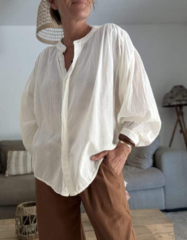 Chemise ample écrue en voile de coton – GIGI La chemise GIGI écrue en voile de coton offre confort, fluidité et élégance pour toutes vos tenues de saison. Sa coupe ample s’adapte du 36 au 42 et met en valeur toutes les silhouettes. Le col Mao et la boutonnière discrète ajoutent une touche contemporaine et minimaliste. Les manches longues se ferment par un bouton raffiné, à porter longues ou retroussées selon vos envies. Le voile de coton léger rend cette pièce agréable même sous des températures estivales. Fabriquée en Italie, elle bénéficie d’une coupe soignée et d’une qualité durable. Sa couleur écrue s’associe facilement avec vos jeans, pantalons en lin ou jupes imprimées. 🧵 Composition : 100 % voile de coton 📏 Taille unique (convient du 36 au 42) 🌿 Coloris : écru 🇮🇹 Fabrication italienne 👕 Coupe : ample 👚 Col : Mao 👖 Manches : longues avec bouton ✨ Détail : boutonnière discrète