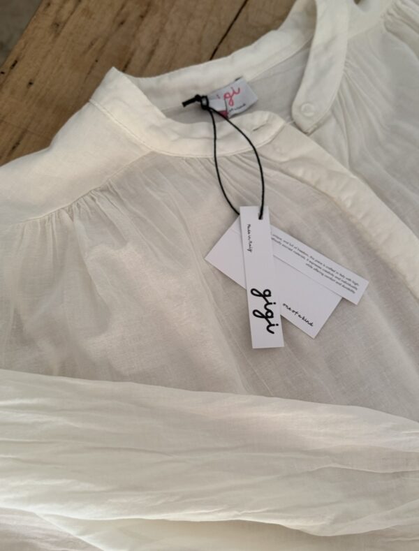 Chemise ample écrue en voile de coton – GIGI La chemise GIGI écrue en voile de coton offre confort, fluidité et élégance pour toutes vos tenues de saison. Sa coupe ample s’adapte du 36 au 42 et met en valeur toutes les silhouettes. Le col Mao et la boutonnière discrète ajoutent une touche contemporaine et minimaliste. Les manches longues se ferment par un bouton raffiné, à porter longues ou retroussées selon vos envies. Le voile de coton léger rend cette pièce agréable même sous des températures estivales. Fabriquée en Italie, elle bénéficie d’une coupe soignée et d’une qualité durable. Sa couleur écrue s’associe facilement avec vos jeans, pantalons en lin ou jupes imprimées. 🧵 Composition : 100 % voile de coton 📏 Taille unique (convient du 36 au 42) 🌿 Coloris : écru 🇮🇹 Fabrication italienne 👕 Coupe : ample 👚 Col : Mao 👖 Manches : longues avec bouton ✨ Détail : boutonnière discrète