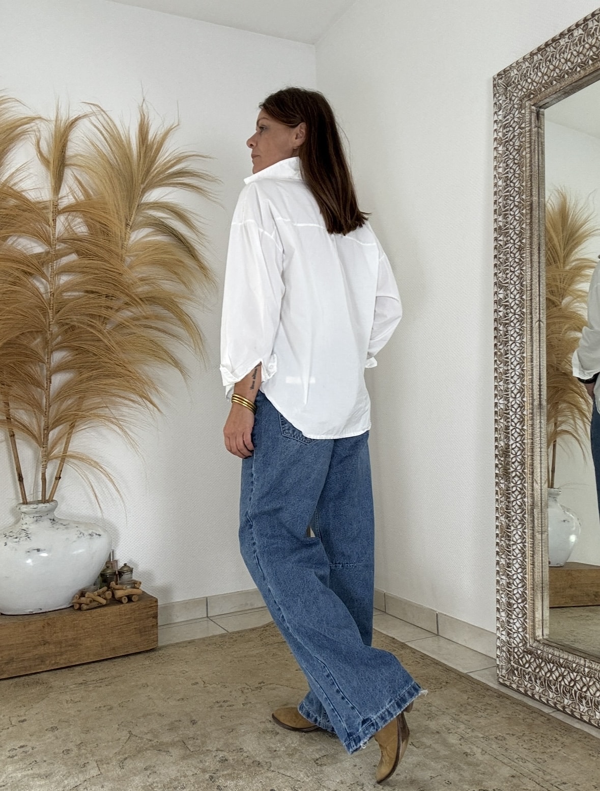 Élégance naturelle et confort absolu La chemise blanche coton oversize Intuition combine douceur, style et liberté de mouvement. Fabriquée en coton respirant, elle promet un confort idéal au quotidien. Sa coupe ample souligne une allure féminine et décontractée. Les manches longues se ferment par un bouton délicat, ajoutant une touche raffinée. Grâce à sa forme fluide, cette chemise s’adapte facilement à votre morphologie. Elle convient parfaitement aux tailles 38 à 42. Une coupe oversize pleine d’aisance Avec sa petite ouverture discrète sur les côtés, la chemise blanche coton oversize laisse le corps respirer. Elle accompagne chaque mouvement avec légèreté. Son col chemise classique structure le look, sans perdre cette touche de douceur que l’on aime tant. Portée ouverte sur un débardeur, ou boutonnée pour un effet plus habillé, elle s’adapte à chaque style. Vous pouvez la porter seule ou la glisser dans un pantalon pour marquer la taille. Des associations harmonieuses La chemise blanche Intuition s’accorde parfaitement avec le pantalon Intuition, disponible en vert agave, camel ou chocolat foncé. Ensemble, ils forment un duo élégant et moderne. Les teintes naturelles se complètent avec équilibre pour un look bohème chic. Grâce à son design intemporel, cette chemise devient un indispensable de votre dressing. Elle se porte aussi bien en semaine qu’en week-end, toujours avec grâce et simplicité.