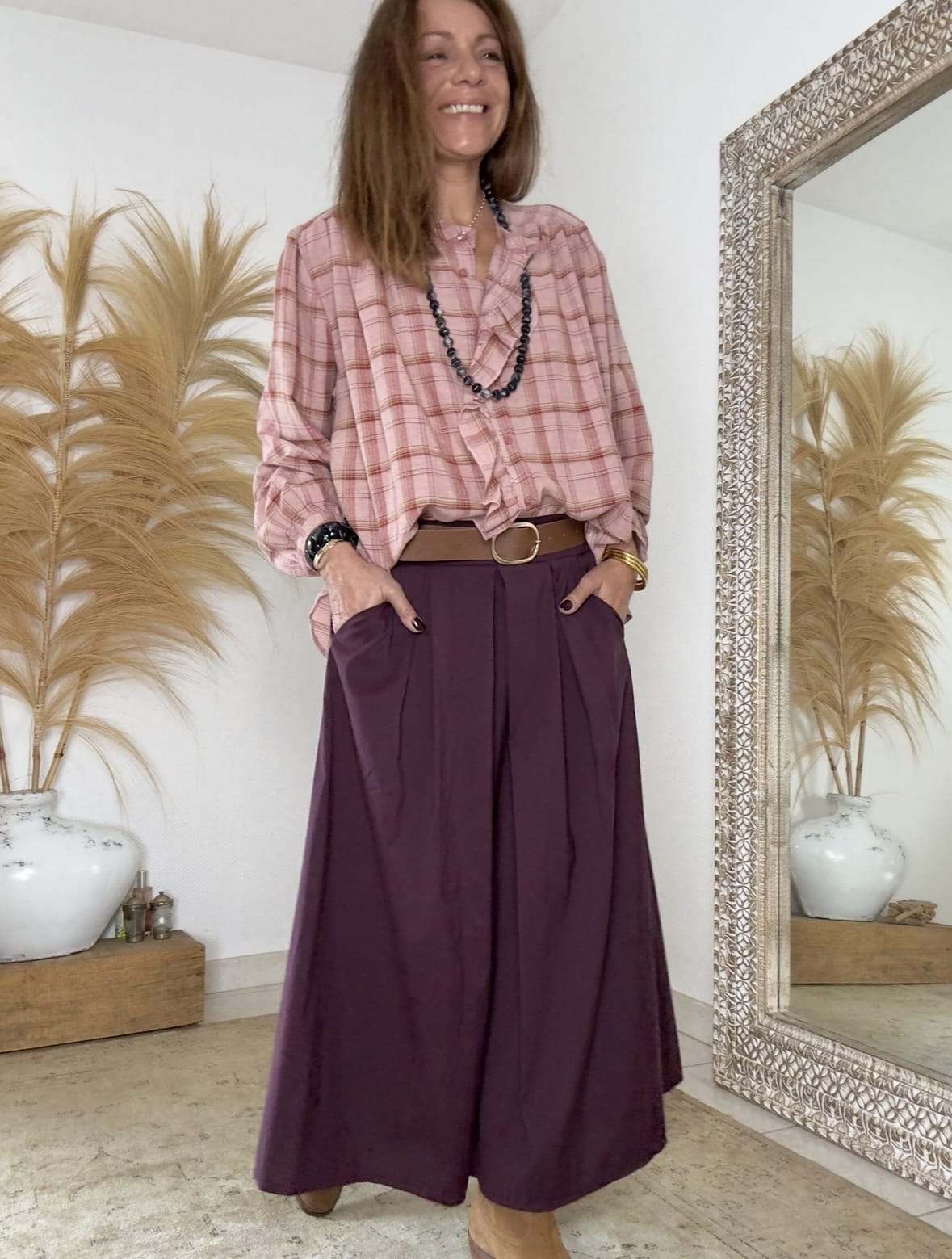 Jupe longue prune fluide à pinces et ceinture assortie. Légèreté, féminité et allure bohème La jupe THAÏS Lou Gloria séduit par sa fluidité, sa coupe élégante et sa couleur prune profonde. Cette teinte vibrante évoque la chaleur de l’automne et s’accorde aisément avec des nuances naturelles. Sa matière légère apporte un tombé souple, tandis que sa forme longue souligne la silhouette sans la marquer. Conçue pour un style bohème chic moderne, la jupe THAÏS s’adapte à toutes les occasions. Elle se porte aussi bien avec une chemise fluide qu’avec un pull doux pour un look plus décontracté. Une coupe fluide et des détails raffinés Le dos élastiqué assure confort et maintien tout au long de la journée. Sur le devant, des pinces délicates apportent structure et féminité. Les poches sur les côtés ajoutent une touche pratique et décontractée, sans rompre la ligne fluide du vêtement. La ceinture assortie, incluse avec la jupe, permet de souligner la taille et d’ajuster la silhouette selon vos envies. La matière souple composée majoritairement de coton offre douceur et légèreté. Son mélange de coton, nylon et élasthanne garantit à la fois confort, tenue et liberté de mouvement. Fabrication italienne et esprit intemporel Fabriquée en Italie, la jupe THAÏS reflète un savoir-faire précis et une qualité durable. Chaque détail a été pensé pour offrir un rendu élégant, féminin et naturel. Sa taille unique (36 à 40) convient à différentes morphologies, tout en mettant en valeur la silhouette. Pour un style complet, associez la jupe THAÏS prune à la chemise Namasté à carreaux Bordeaux ou à la veste Lénaïc Bordeaux. L’ensemble crée un contraste harmonieux et une allure bohème chic, douce et moderne à la fois. La jupe THAÏS deviendra vite une pièce essentielle du dressing féminin, alliant confort, élégance et authenticité.