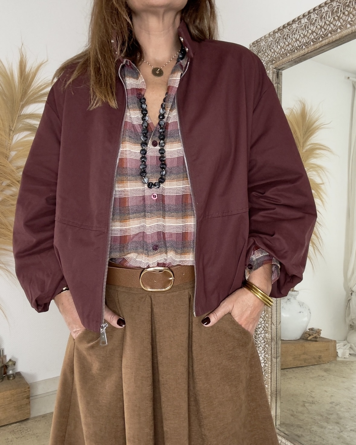 LENAÏC, la veste bordeaux au charme Intuition La veste LENAÏC de la marque Intuition séduit par son équilibre entre confort et élégance. Sa couleur bordeaux profonde attire le regard et valorise le teint. Sa matière douce et fluide épouse la silhouette avec naturel. Entièrement doublée, elle assure un confort agréable et une tenue harmonieuse. Ainsi, LENAÏC devient une pièce incontournable de mi-saison. Une coupe boule plate, féminine et actuelle Sa forme boule plate ajoute du volume sans épaissir la ligne. La silhouette reste souple, moderne et légèrement arrondie. La taille unique convient du 36 au 40 selon le rendu souhaité. De plus, le tombé fluide apporte légèreté et féminité. Cette veste s’adapte aussi bien à un style urbain qu’à une allure bohème. Des détails qui font la différence La fermeture zippée est pratique et élégante. Le bouton du col montant ajoute une touche chic et contemporaine. Les manches, plus longues que trois quarts, libèrent joliment le poignet. Les finitions discrètes témoignent d’un vrai soin de confection. Enfin, la doublure intégrale garantit une structure stable et douce. Un style fluide et des associations parfaites Le coloris bordeaux s’accorde naturellement avec les tons camel, écru ou beige. Cette teinte chaude met en valeur les peaux claires comme dorées. Portez LENAÏC sur un jean pour un look citadin élégant. Elle s’accorde aussi parfaitement avec la jupe Flora et la chemise Namasté, pour un ensemble féminin et harmonieux. Une matière douce et naturelle Confectionnée en 100% coton, LENAÏC allie confort et légèreté. La matière est respirante, agréable et résistante. Elle conserve sa souplesse tout au long de la journée. Ainsi, la veste accompagne chaque mouvement avec fluidité et aisance. En résumé La veste LENAÏC bordeaux Intuition allie modernité, douceur et confort. Sa coupe boule plate et son col montant créent une silhouette élégante. Entièrement doublée, elle s’associe à merveille avec la chemise Namasté et la jupe Flora. Un modèle intemporel et féminin, à adopter sans hésiter.