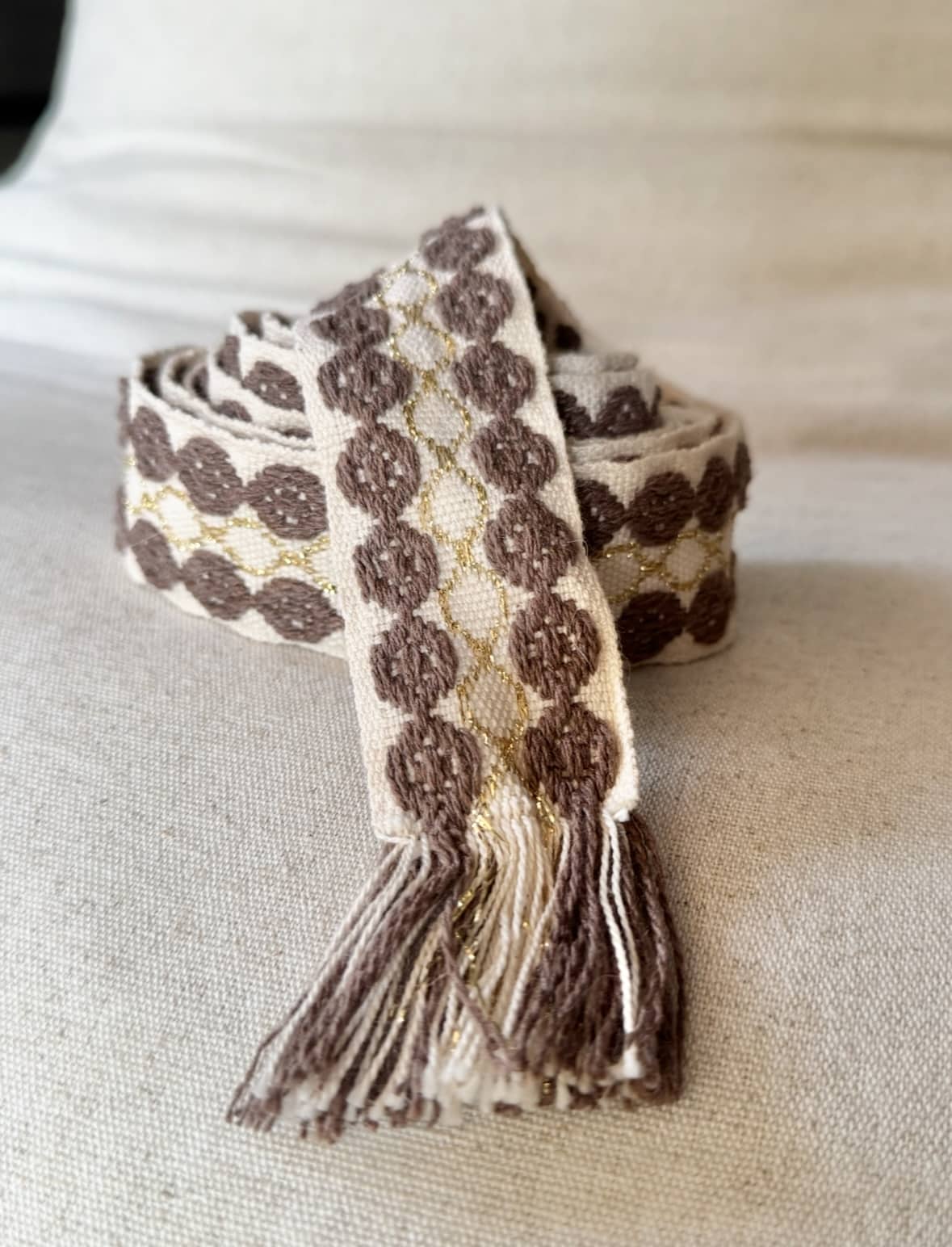 L’accessoire bohème chic par excellence La ceinture POLIG incarne l’élégance décontractée du style bohème chic. Confectionnée en coton doux, elle offre à la fois souplesse, texture et charme artisanal. Ses motifs ronds brodés couleur chocolat rappellent le travail soigné des pièces faites à la main. Le liseré doré apporte une touche de lumière et de féminité, idéale pour rehausser vos tenues. Grâce à sa matière naturelle, la ceinture POLIG reste agréable et facile à ajuster. Elle se noue simplement à la taille ou sur les hanches, selon votre style. Ses finitions à franges ajoutent un esprit libre et délicatement vintage. Chaque détail contribue à une allure féminine, naturelle et authentique. Trois coloris, trois ambiances La ceinture POLIG se décline en trois teintes élégantes et faciles à assortir : Beige : douce et lumineuse, parfaite sur une robe fluide ou une jupe claire. Kaki : naturelle et subtile, idéale pour des looks automnaux et raffinés. Camel : chaleureuse et intemporelle, un indispensable de la saison. Portée sur une robe vaporeuse, une jupe longue ou un pantalon fluide, elle structure la silhouette tout en conservant sa légèreté. Elle se noue selon vos envies : en simple tour pour un style épuré, ou en double pour un effet plus affirmé. Une signature Les Marques de Lilo La ceinture POLIG incarne parfaitement l’univers Les Marques de Lilo : un style féminin, doux et naturellement bohème. Légère, polyvalente et unique, elle complète avec grâce vos tenues du quotidien. Ses détails brodés et sa finition à franges en font un accessoire plein de caractère. Un simple nœud suffit pour souligner la taille et révéler toute votre allure bohème chic.