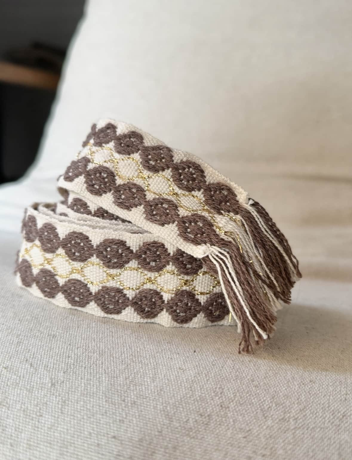 L’accessoire bohème chic par excellence La ceinture POLIG incarne l’élégance décontractée du style bohème chic. Confectionnée en coton doux, elle offre à la fois souplesse, texture et charme artisanal. Ses motifs ronds brodés couleur chocolat rappellent le travail soigné des pièces faites à la main. Le liseré doré apporte une touche de lumière et de féminité, idéale pour rehausser vos tenues. Grâce à sa matière naturelle, la ceinture POLIG reste agréable et facile à ajuster. Elle se noue simplement à la taille ou sur les hanches, selon votre style. Ses finitions à franges ajoutent un esprit libre et délicatement vintage. Chaque détail contribue à une allure féminine, naturelle et authentique. Trois coloris, trois ambiances La ceinture POLIG se décline en trois teintes élégantes et faciles à assortir : Beige : douce et lumineuse, parfaite sur une robe fluide ou une jupe claire. Kaki : naturelle et subtile, idéale pour des looks automnaux et raffinés. Camel : chaleureuse et intemporelle, un indispensable de la saison. Portée sur une robe vaporeuse, une jupe longue ou un pantalon fluide, elle structure la silhouette tout en conservant sa légèreté. Elle se noue selon vos envies : en simple tour pour un style épuré, ou en double pour un effet plus affirmé. Une signature Les Marques de Lilo La ceinture POLIG incarne parfaitement l’univers Les Marques de Lilo : un style féminin, doux et naturellement bohème. Légère, polyvalente et unique, elle complète avec grâce vos tenues du quotidien. Ses détails brodés et sa finition à franges en font un accessoire plein de caractère. Un simple nœud suffit pour souligner la taille et révéler toute votre allure bohème chic.