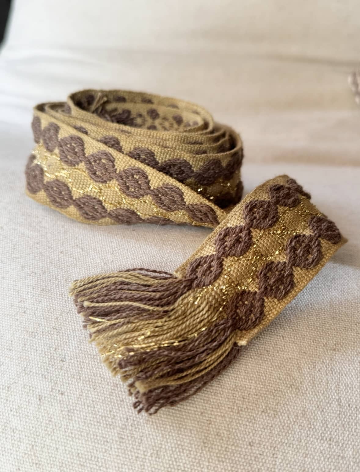 L’accessoire bohème chic par excellence La ceinture POLIG incarne l’élégance décontractée du style bohème chic. Confectionnée en coton doux, elle offre à la fois souplesse, texture et charme artisanal. Ses motifs ronds brodés couleur chocolat rappellent le travail soigné des pièces faites à la main. Le liseré doré apporte une touche de lumière et de féminité, idéale pour rehausser vos tenues. Grâce à sa matière naturelle, la ceinture POLIG reste agréable et facile à ajuster. Elle se noue simplement à la taille ou sur les hanches, selon votre style. Ses finitions à franges ajoutent un esprit libre et délicatement vintage. Chaque détail contribue à une allure féminine, naturelle et authentique. Trois coloris, trois ambiances La ceinture POLIG se décline en trois teintes élégantes et faciles à assortir : Beige : douce et lumineuse, parfaite sur une robe fluide ou une jupe claire. Kaki : naturelle et subtile, idéale pour des looks automnaux et raffinés. Camel : chaleureuse et intemporelle, un indispensable de la saison. Portée sur une robe vaporeuse, une jupe longue ou un pantalon fluide, elle structure la silhouette tout en conservant sa légèreté. Elle se noue selon vos envies : en simple tour pour un style épuré, ou en double pour un effet plus affirmé. Une signature Les Marques de Lilo La ceinture POLIG incarne parfaitement l’univers Les Marques de Lilo : un style féminin, doux et naturellement bohème. Légère, polyvalente et unique, elle complète avec grâce vos tenues du quotidien. Ses détails brodés et sa finition à franges en font un accessoire plein de caractère. Un simple nœud suffit pour souligner la taille et révéler toute votre allure bohème chic.