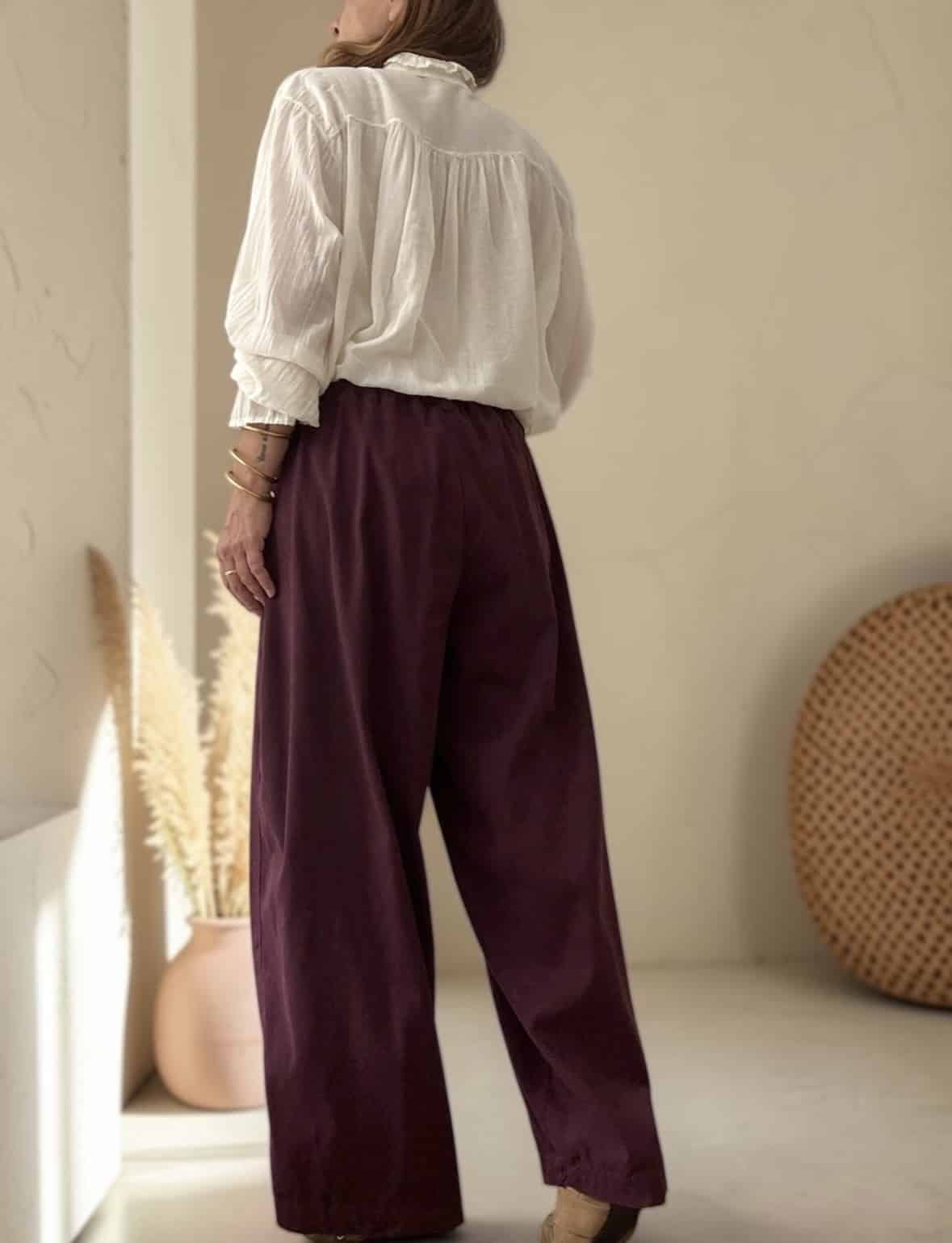 Détail taille élastiquée au dos et fermeture zip bouton du pantalon Allane aubergine.