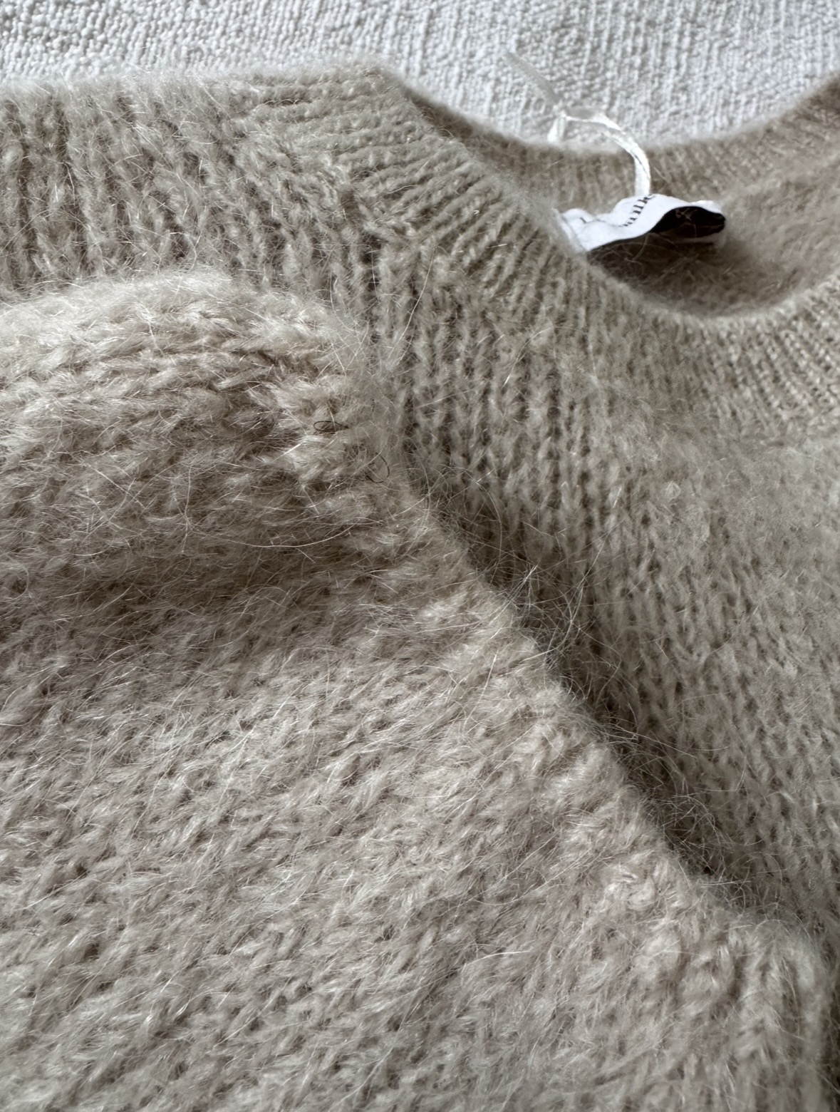 Détail de la maille du pull beige avec 40 % de kid mohair, toucher doux et aspect duveteux.